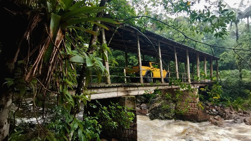 Joinville-SC: caminhonete amarela passandro sobre ponte de madeira coberta sobre o rio com vegetação na região da Estrada Bonita.