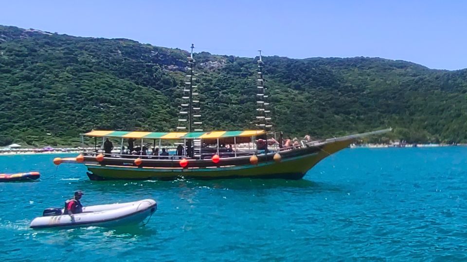 Barco de turismo navega em frente às Prainhas do Pontal do Atalaia, com sua famosa escadaria e mar azul-turquesa