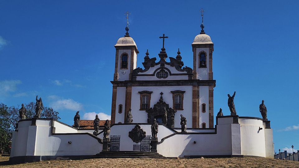 O Santuário Bom Jesus do Matosinhos é uma das obras mais espetaculares do Barroco Brasileiro; a igreja branca com detalhes em pedra e ao redor do adro estão as 12 imagens entalhadas em pedra sabão pelo Mestre Aleijadinho