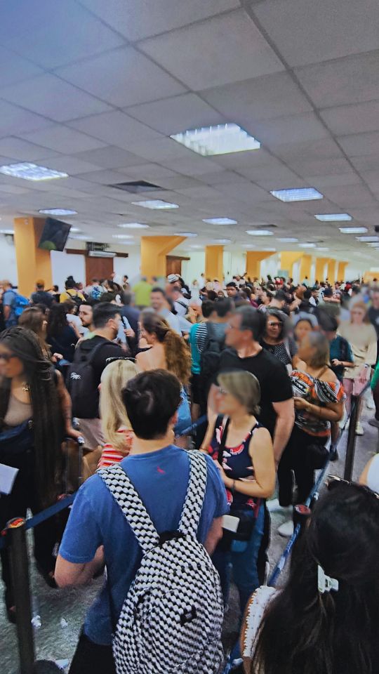 Área do Check-in presencial com uma longa fila de passageiros aguardando.