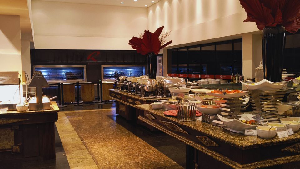 O enorme buffet de pratos, quentes, saladas e sobremesas. Ao fundo As grandes churrasqueiras que assam as deliciosas carnes