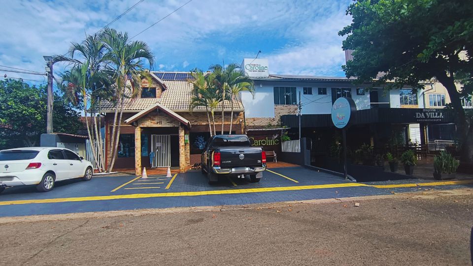 Fachada da Pousada Caroline em Foz do Iguaçu com algumas vagas de estacionamento em frente