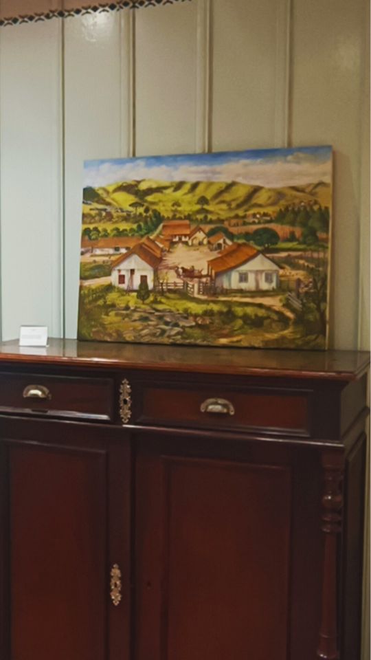 Uma pintura que representa a história da Colônia Witmarsum sobre um móvel de madeira, tradição da cultura dos imigrantes Menonitas